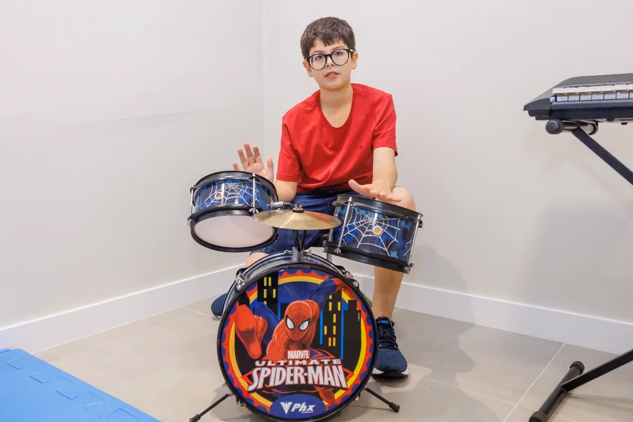 Child playing a children's drum kit in the music therapy room.