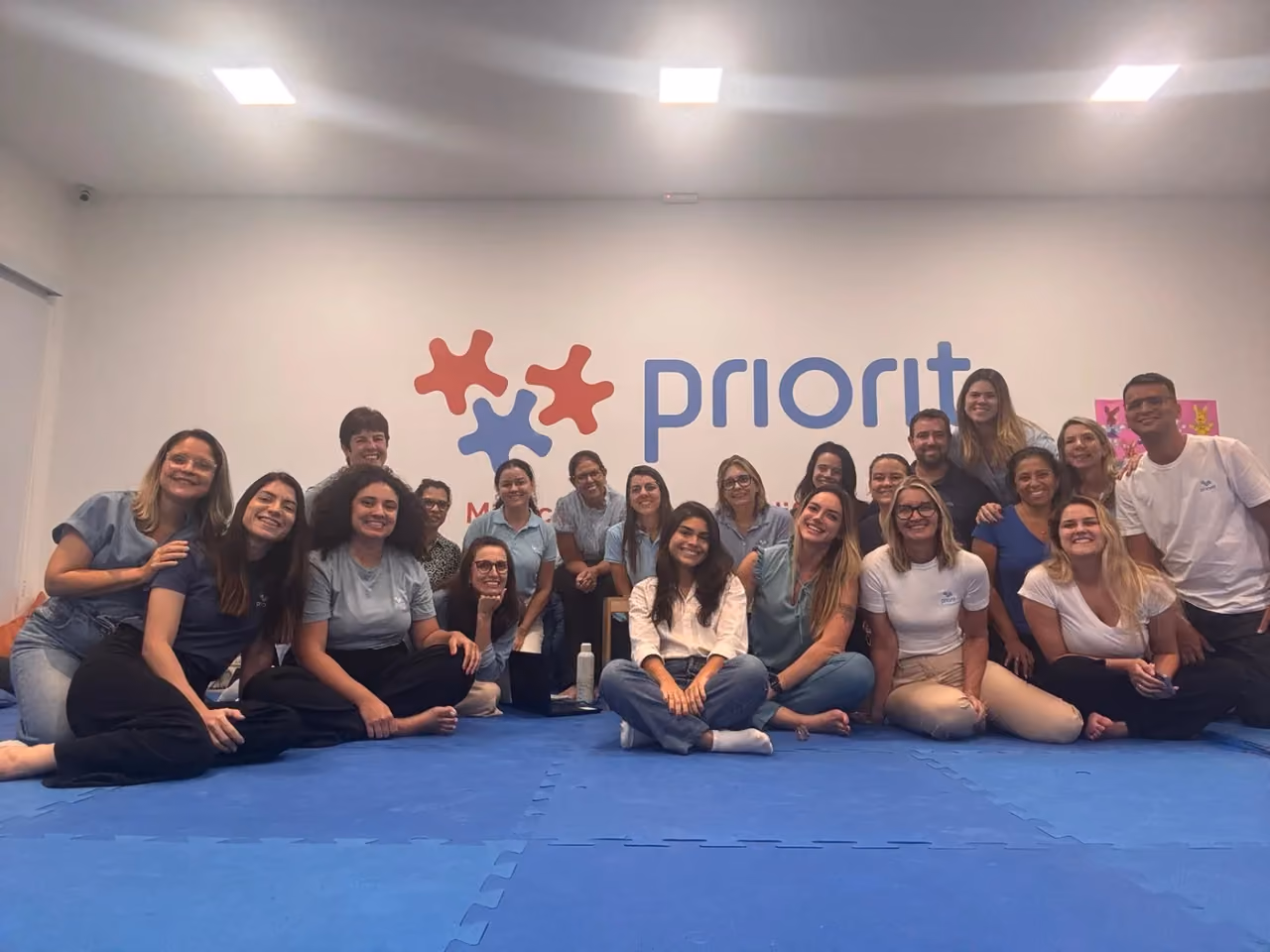 Equipe do Instituto Priorit reunida sobre o tatame, diante do painel da marca. - 1 de 2