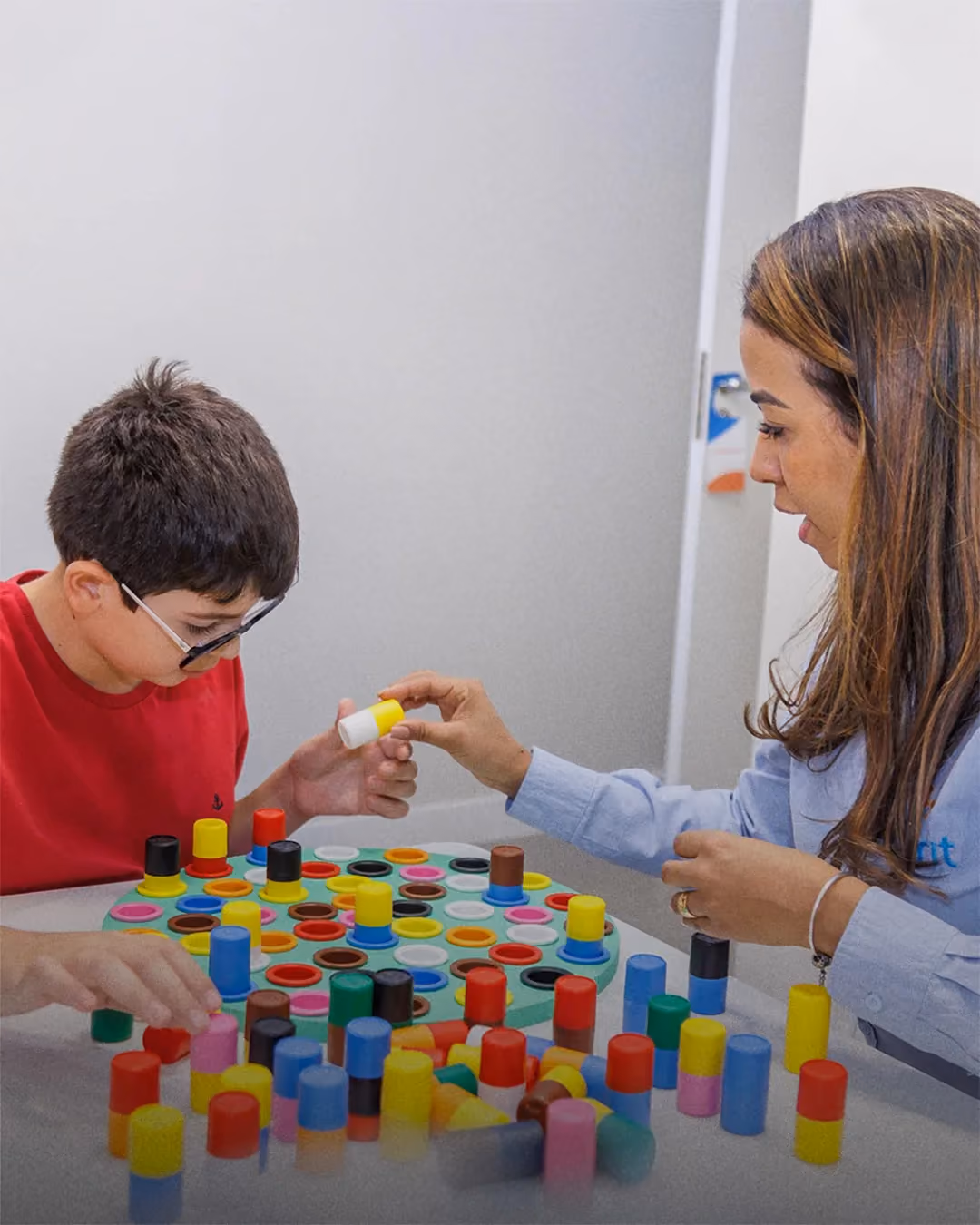 Criatura y psicóloga apilando bloques de colores durante la sesión. - 2 de 2