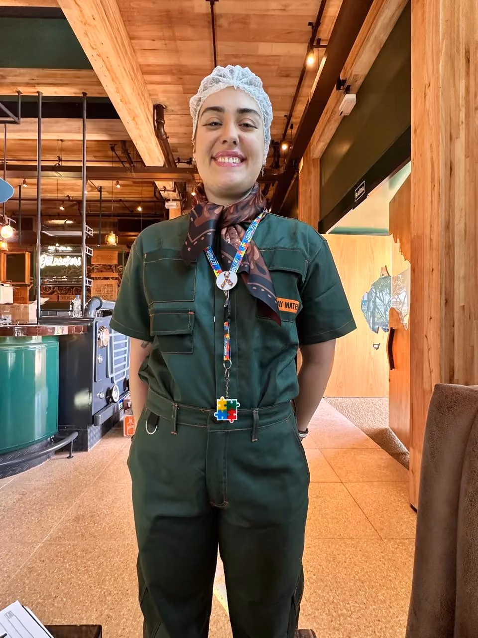 Jovem do Núcleo de Emprego Apoiado uniformizado em seu posto de trabalho.