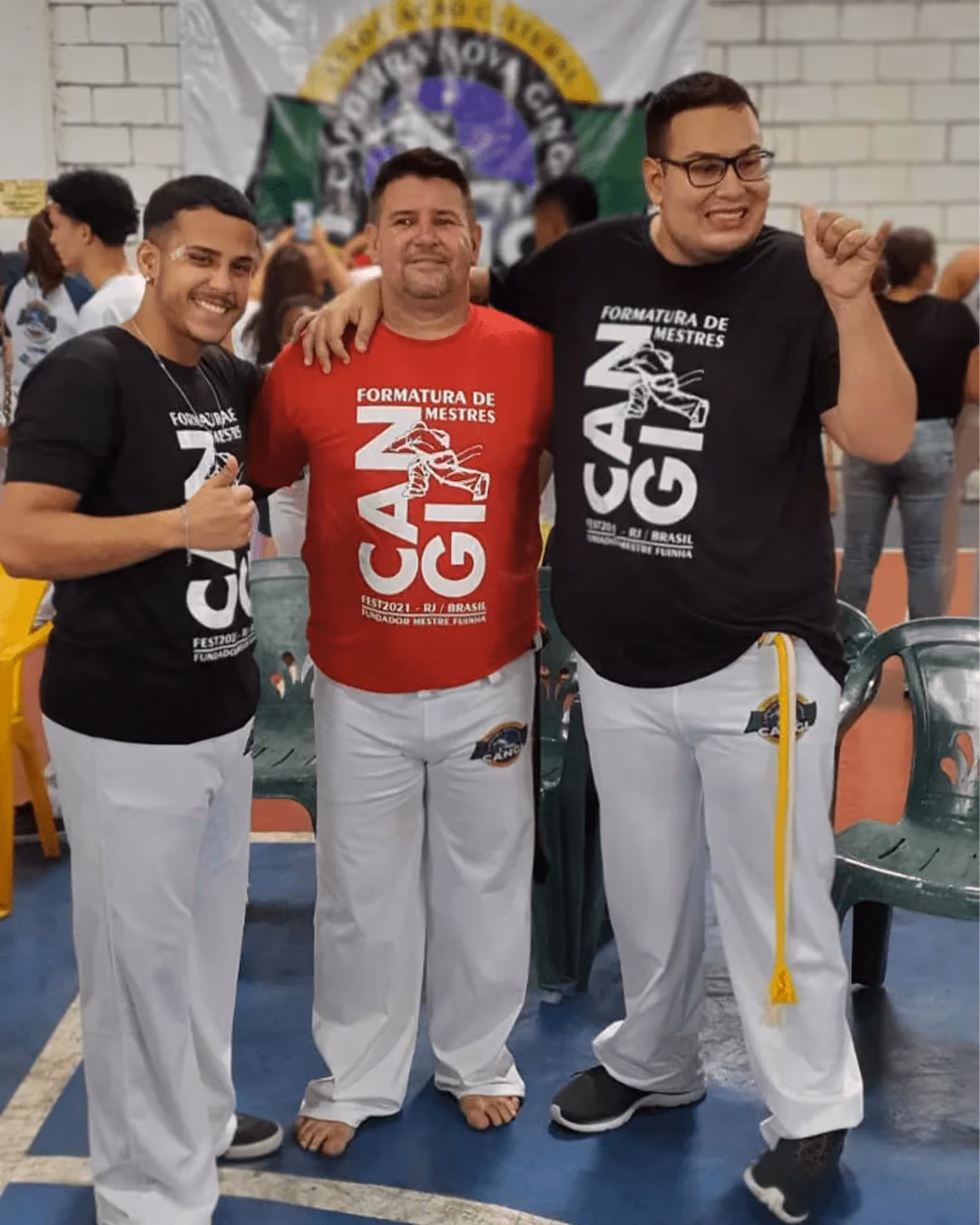 Three adult capoeiristas posing with a berimbau at a group gathering. - 3 de 4