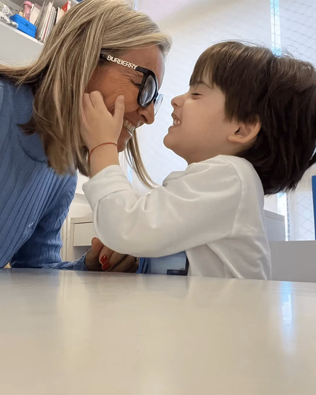 Fonoaudióloga frente a frente com uma criança em exercício de imitação orofacial. - 3 de 5