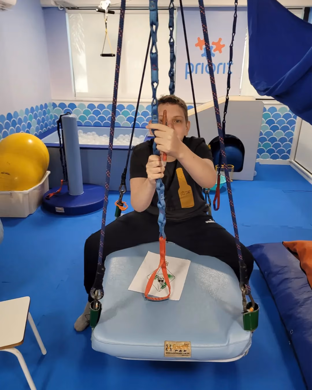 Jovem em balanço de suporte na sala de integração sensorial.