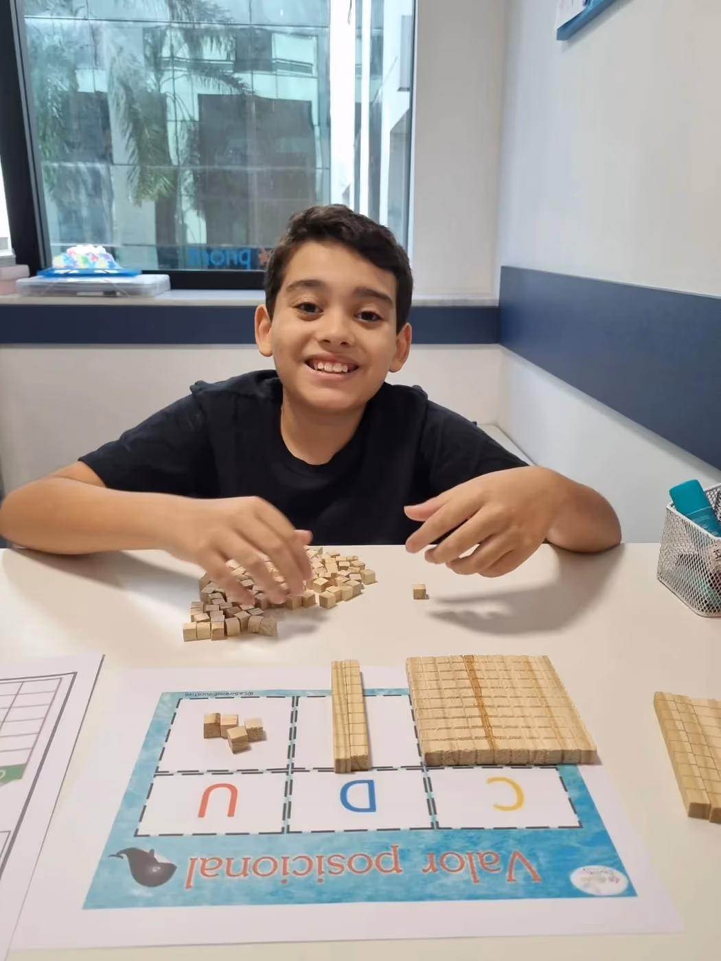 Criatura sonriendo durante una actividad con material dorado y tablero de valor posicional.